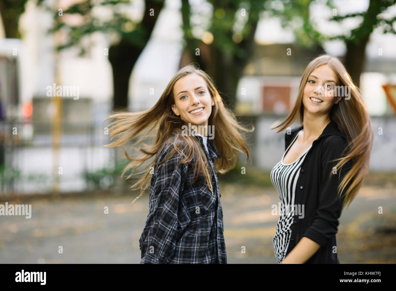 Porträt von zwei Junge weibliche Freunde wirbelnden lange braune Haare in Park Stockfoto