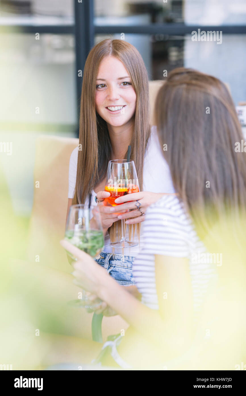 Zwei junge weibliche Freunde über Cocktails an Sidewalk Cafe chatten Stockfoto