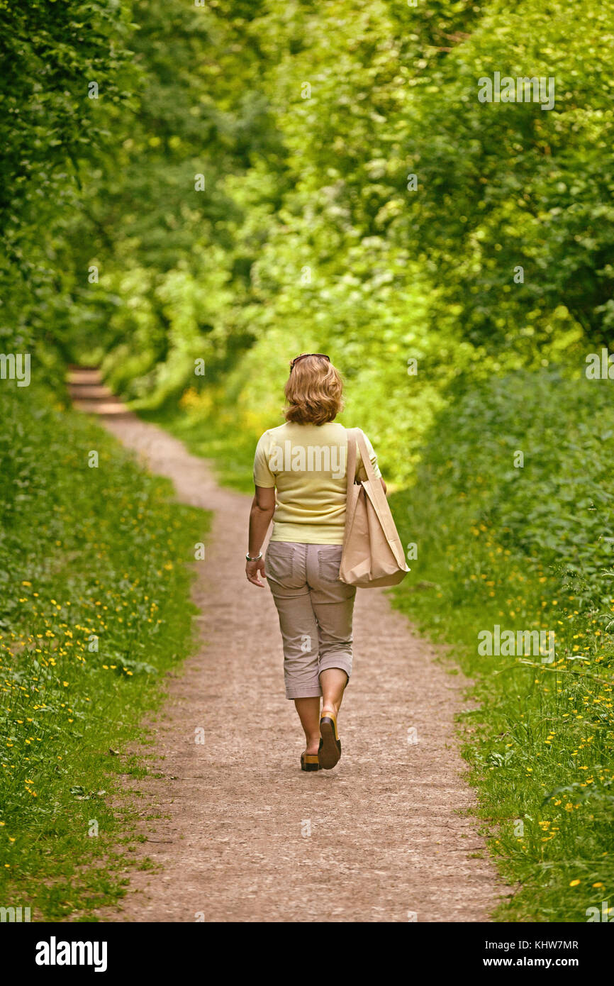 Eine Frau, die durch einen Fußweg auf einem hellen, sonnigen Tag Stockfoto