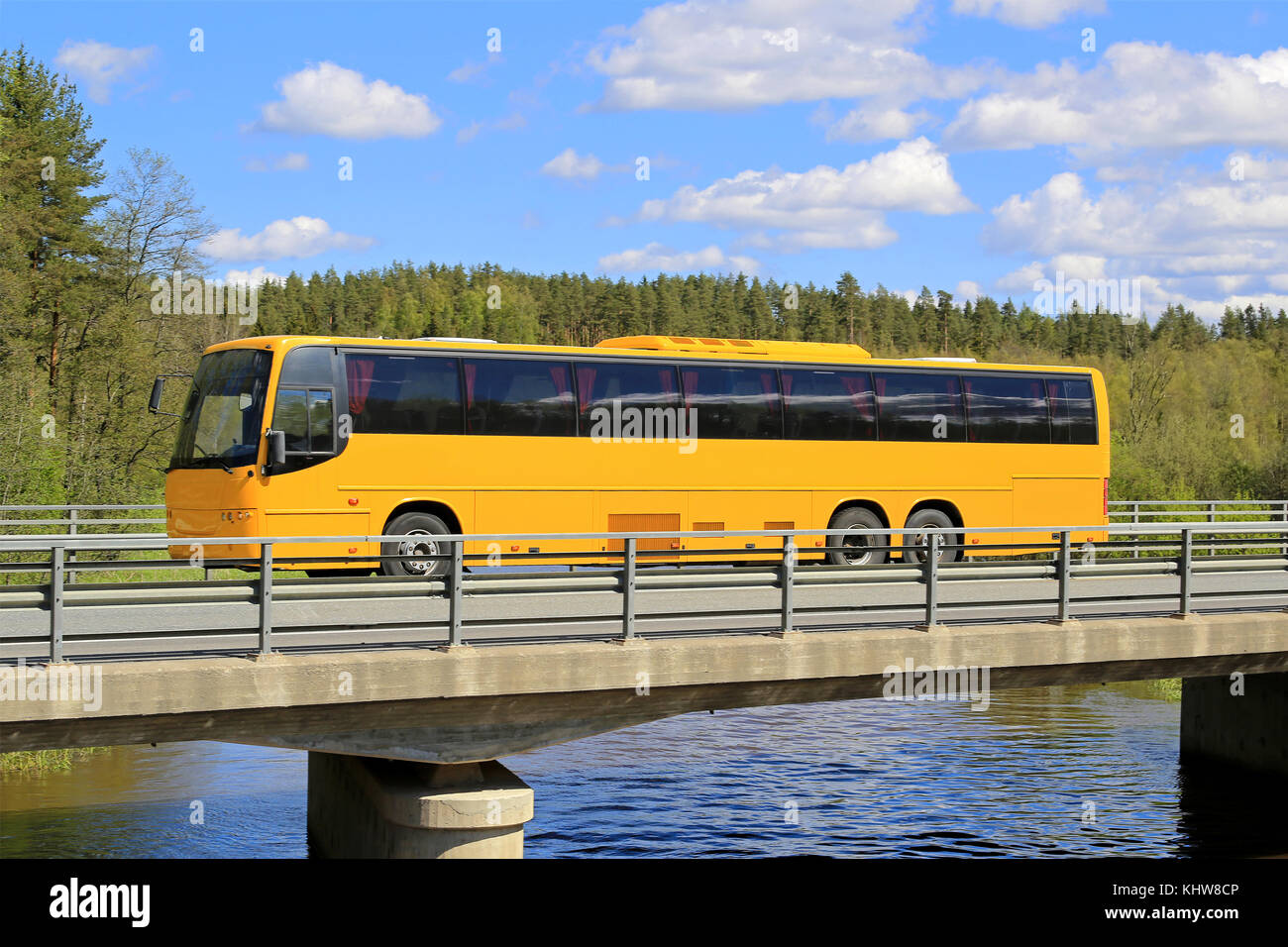 Gelber Reisebus, der an einem schönen Sommertag entlang der malerischen Brücke fährt. Stockfoto