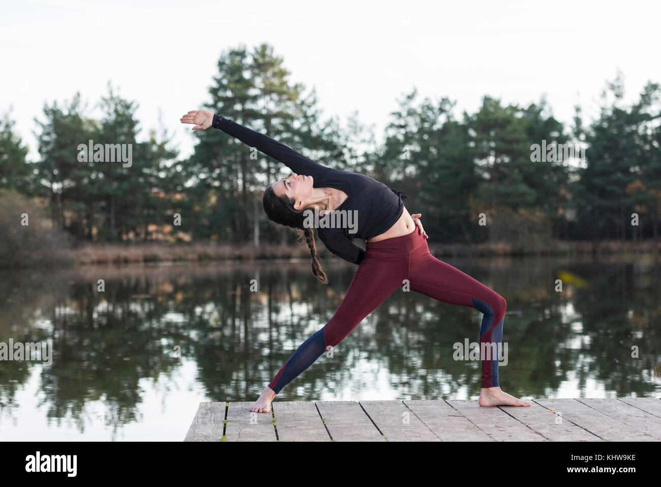 Frau Yoga durch einen See, eine umgekehrte Krieger darstellen. Stockfoto