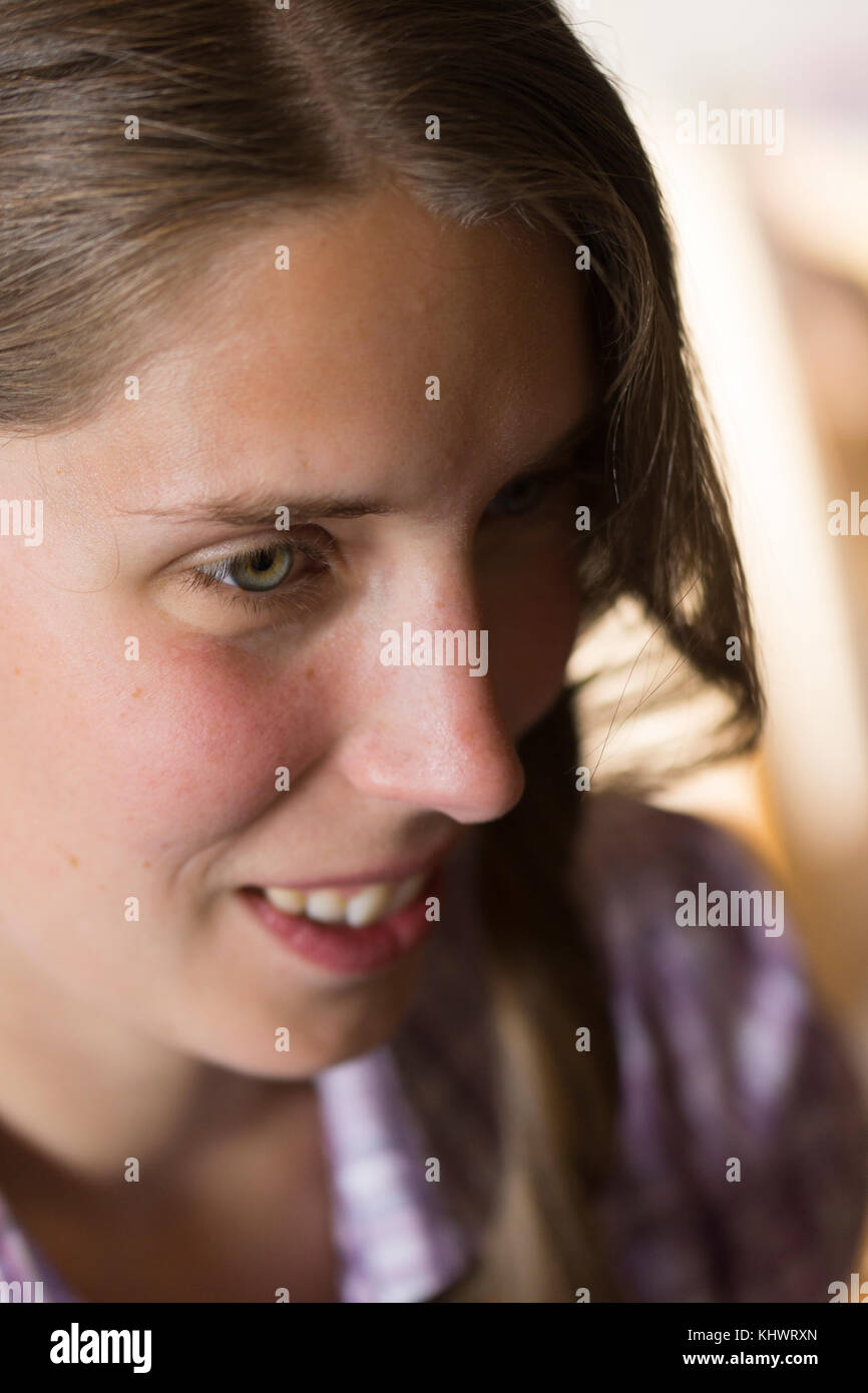 Eine junge Frau in den 20er Jahren mit dem Gesicht zur Hälfte in Schatten und Kontemplation Stockfoto