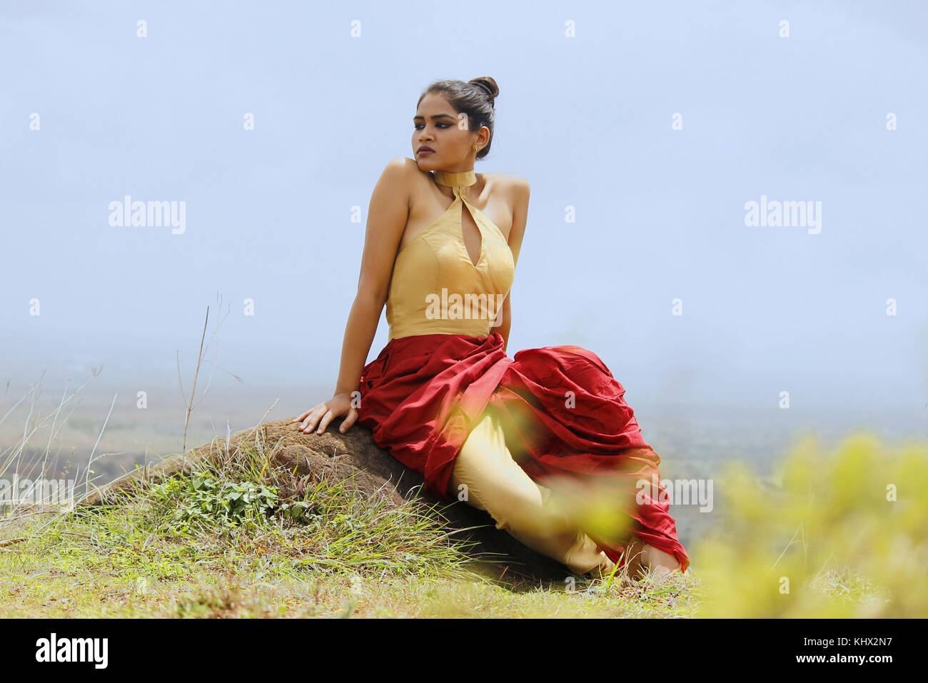 Junge Frau in der indischen Kleid mit Hügel im Hintergrund in den Himmel schauend Stockfoto