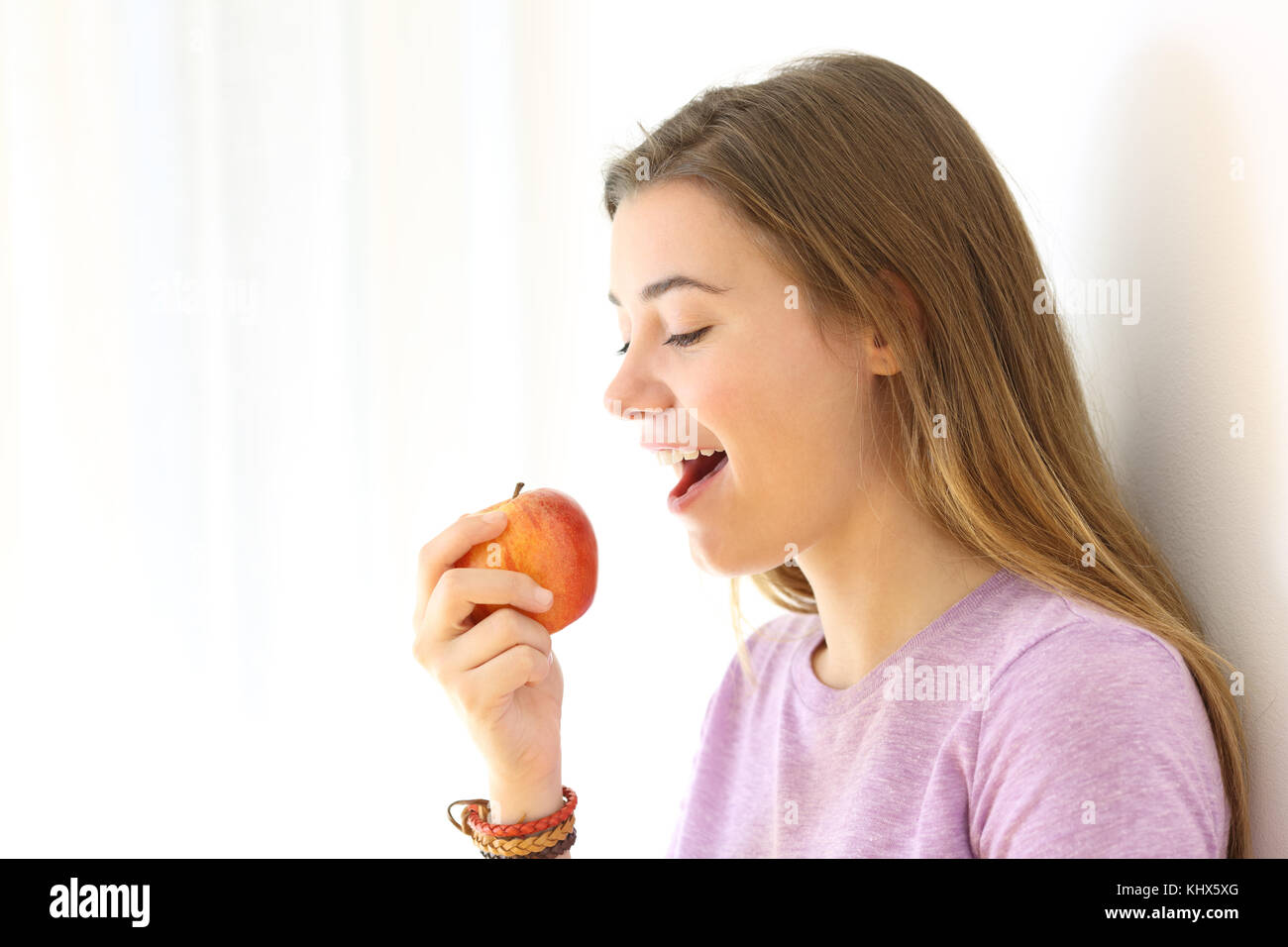 Portrait Of Happy Teen das Essen eines Apfels auf Weiß an der Seite isoliert Stockfoto