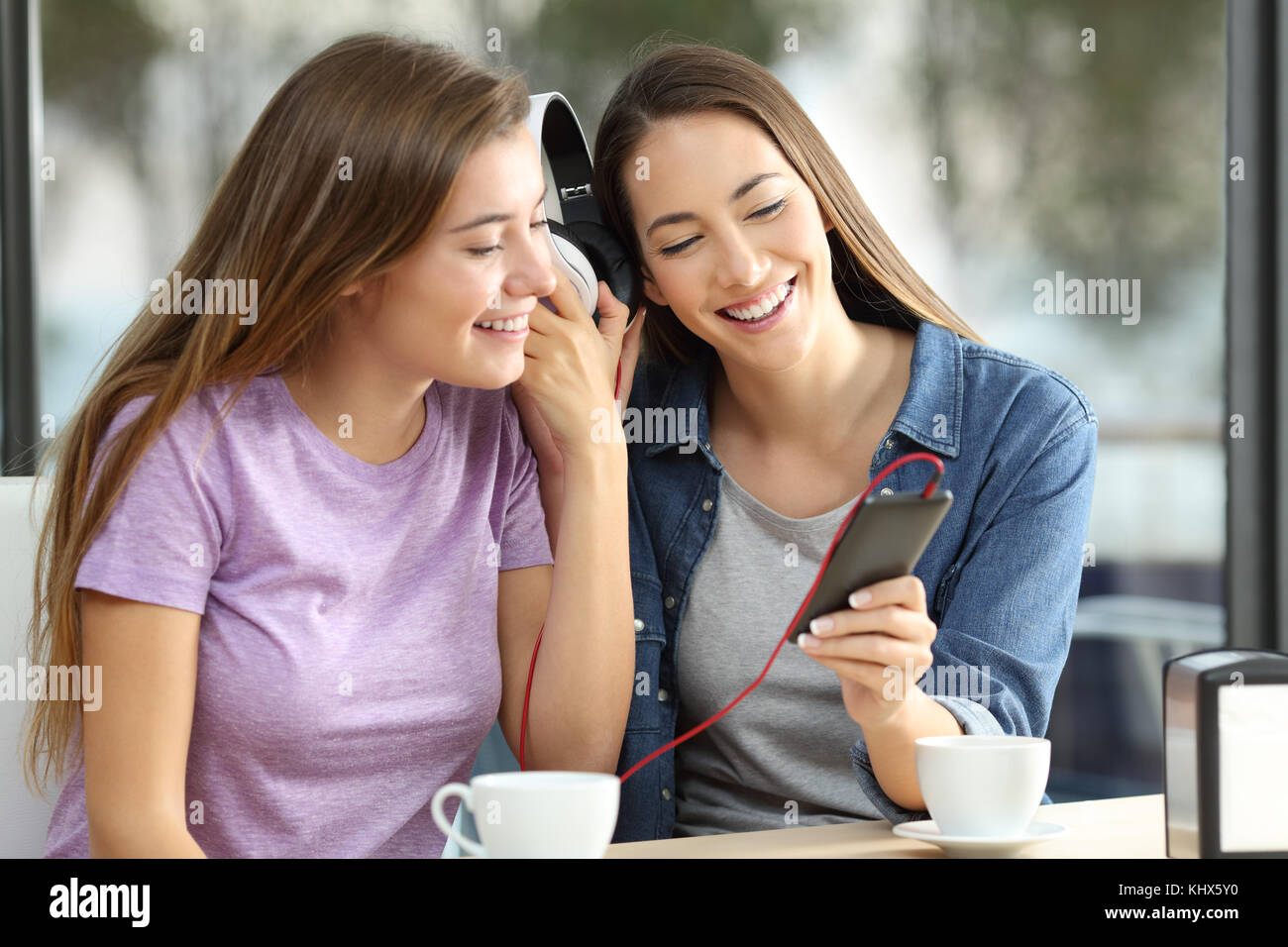 Zwei glückliche Freunde teilen auf Linie Musik sitzen in einer Bar Stockfoto