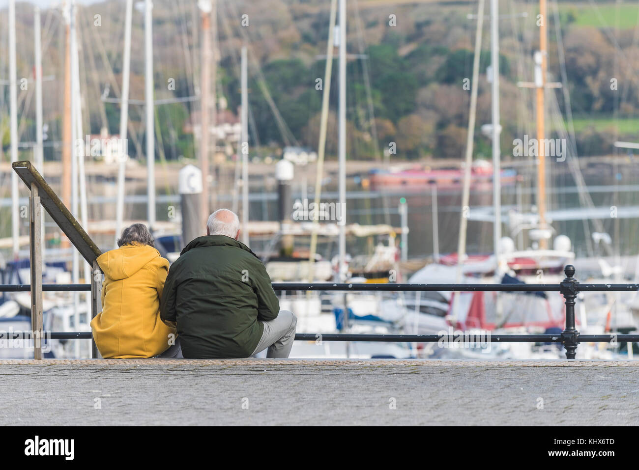 Ein reifes Paar Leute zusammen sitzen auf Schritte mit Blick auf eine Marina in Falmouth Cornwall UK. Stockfoto