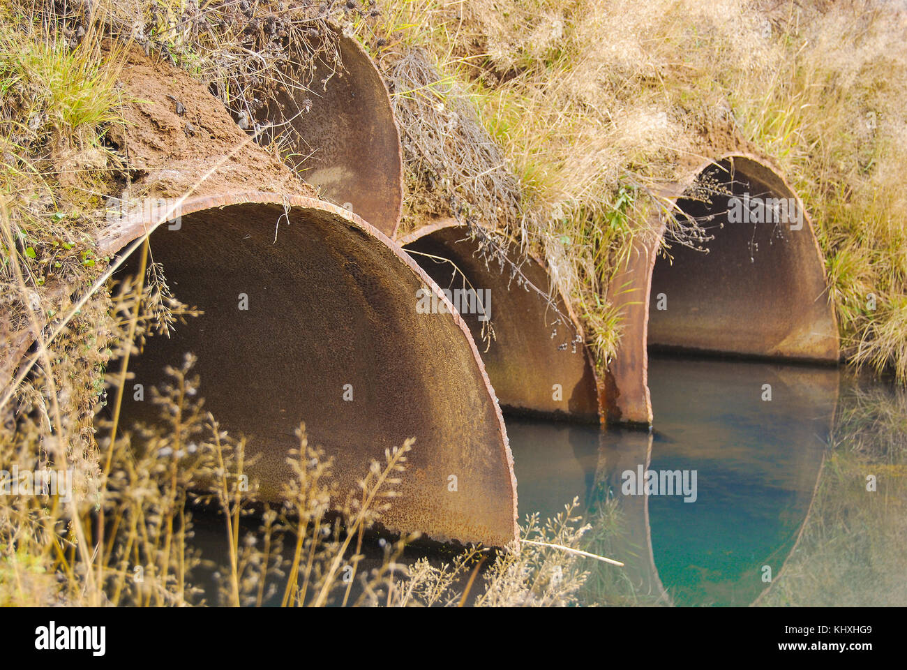 Große rostige Metallrohre unter der Brücke für den Übergang von Wasser Stockfoto