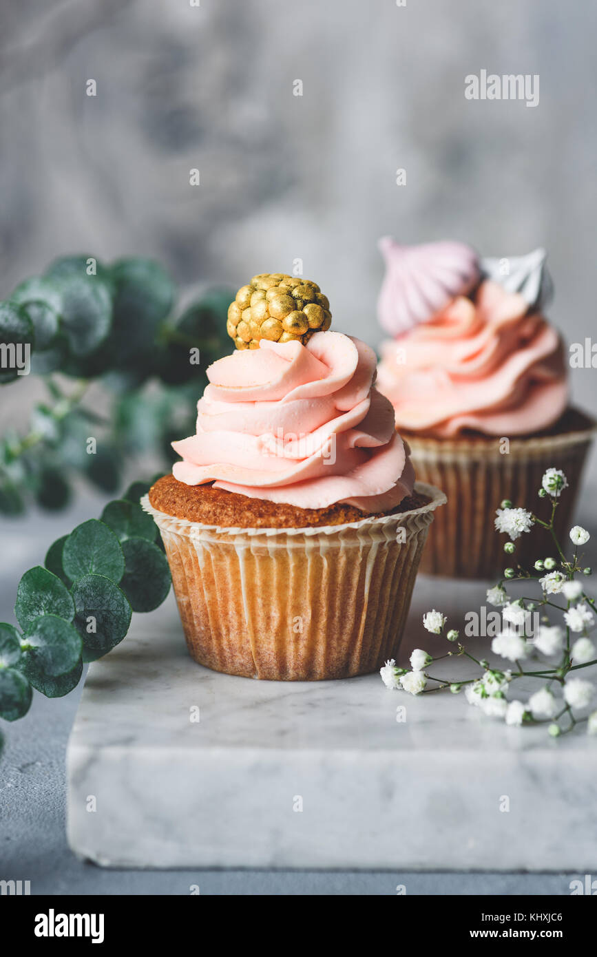 Cupcakes mit coral Creme und goldenen Verzierungen auf einem Brett. Hochzeit Cupcakes. Getonten Bild, selektiver Fokus Stockfoto