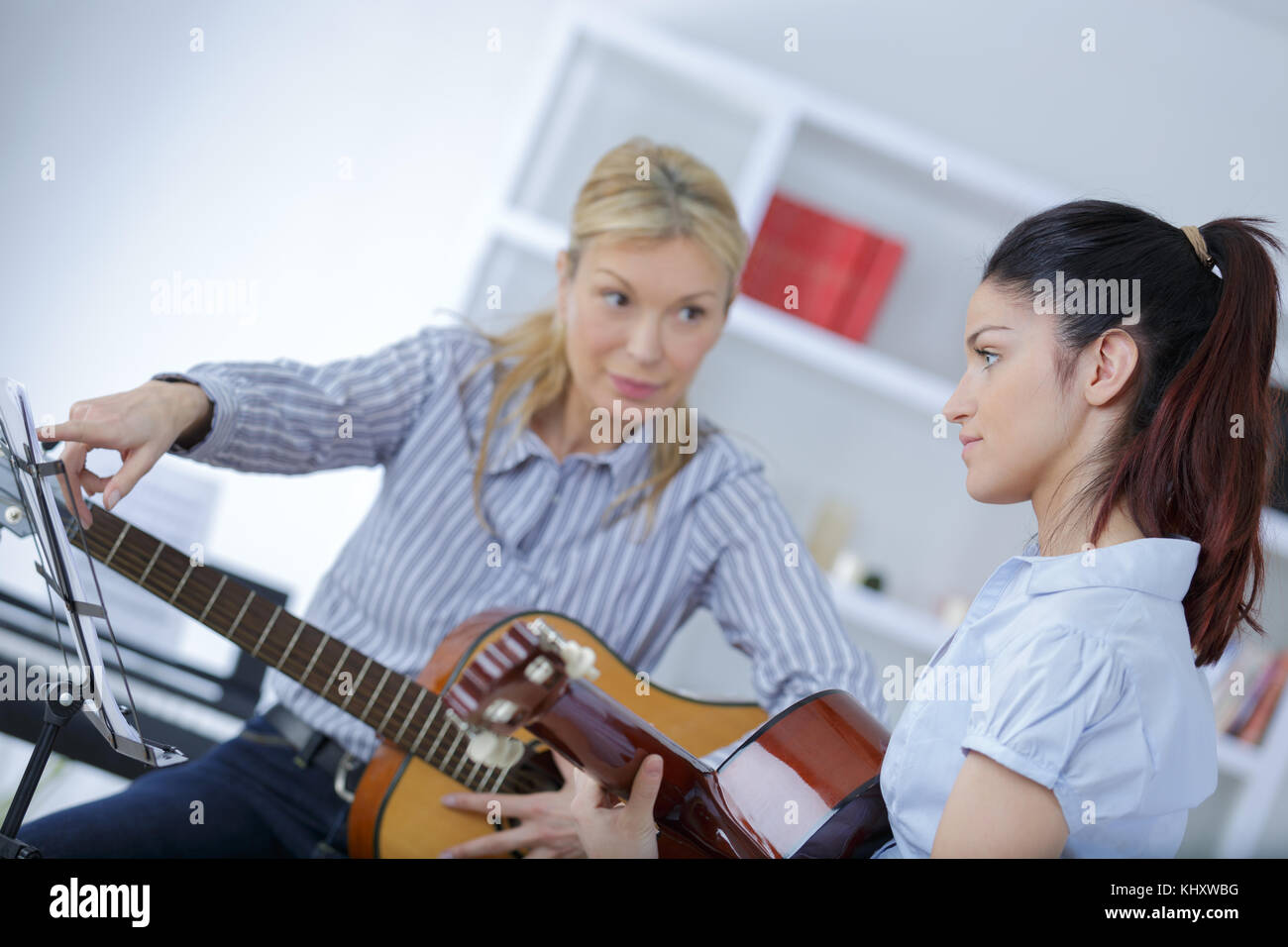 Reife weibliche Lehre ihre Schüler, wie Gitarre zu spielen. Stockfoto