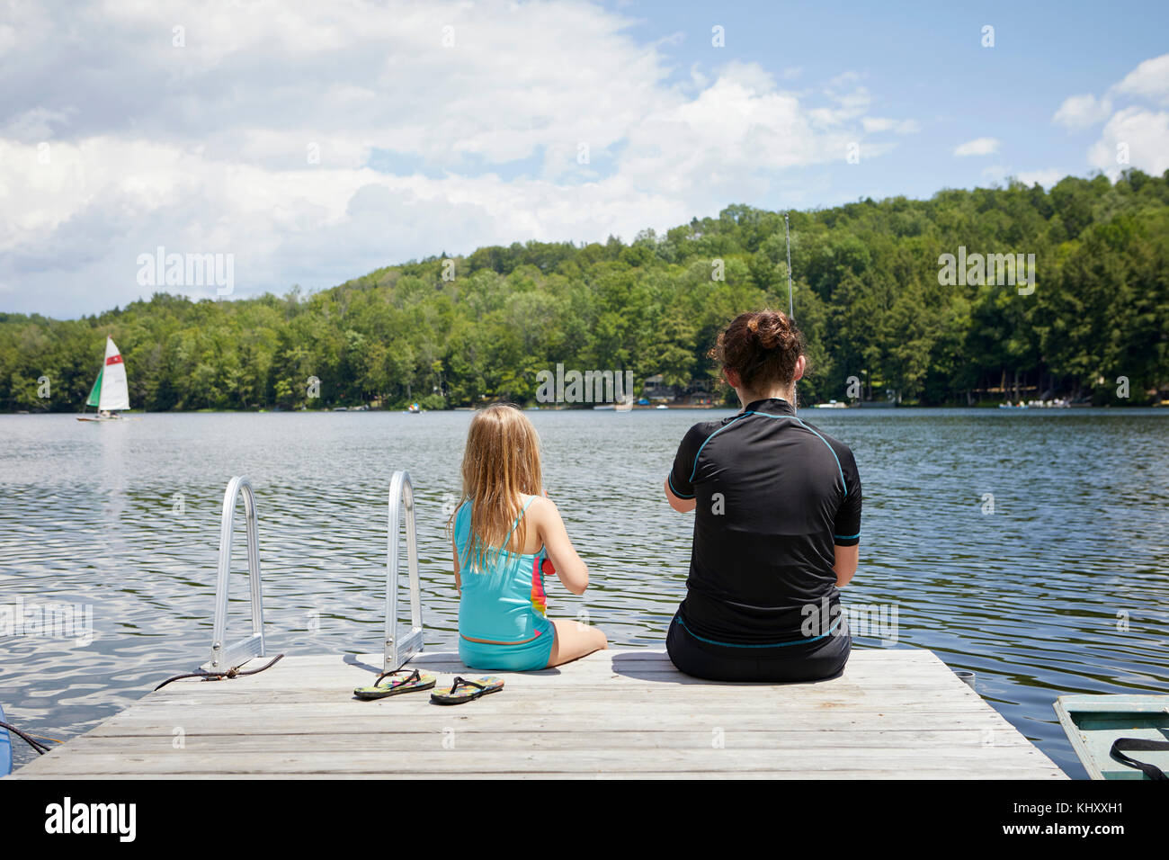 Zwei junge Mädchen sitzen auf Jetty, Rückansicht Stockfoto