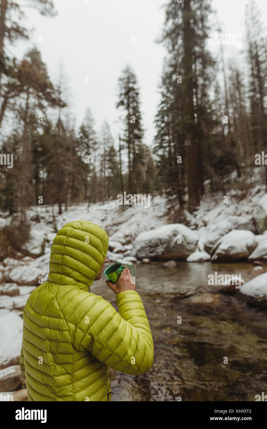 Männliche Wanderer, Kaffee trinken, während Sie am Fluss im verschneiten Sequoia National Park, Kalifornien, USA Stockfoto