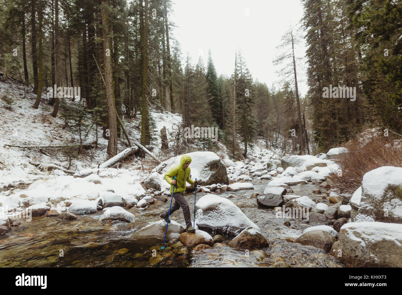Männliche Wanderer über Fluss Felsen im verschneiten Sequoia National Park, Kalifornien, USA Stockfoto