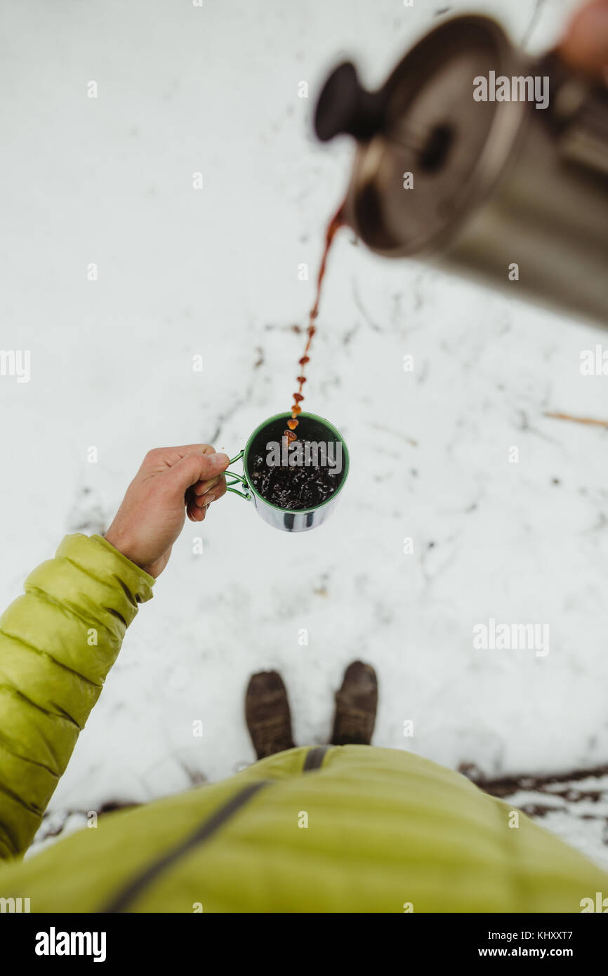 Persönliche Perspektive der männlichen Wanderer Kaffee Gießen von Kolben im Schnee Stockfoto
