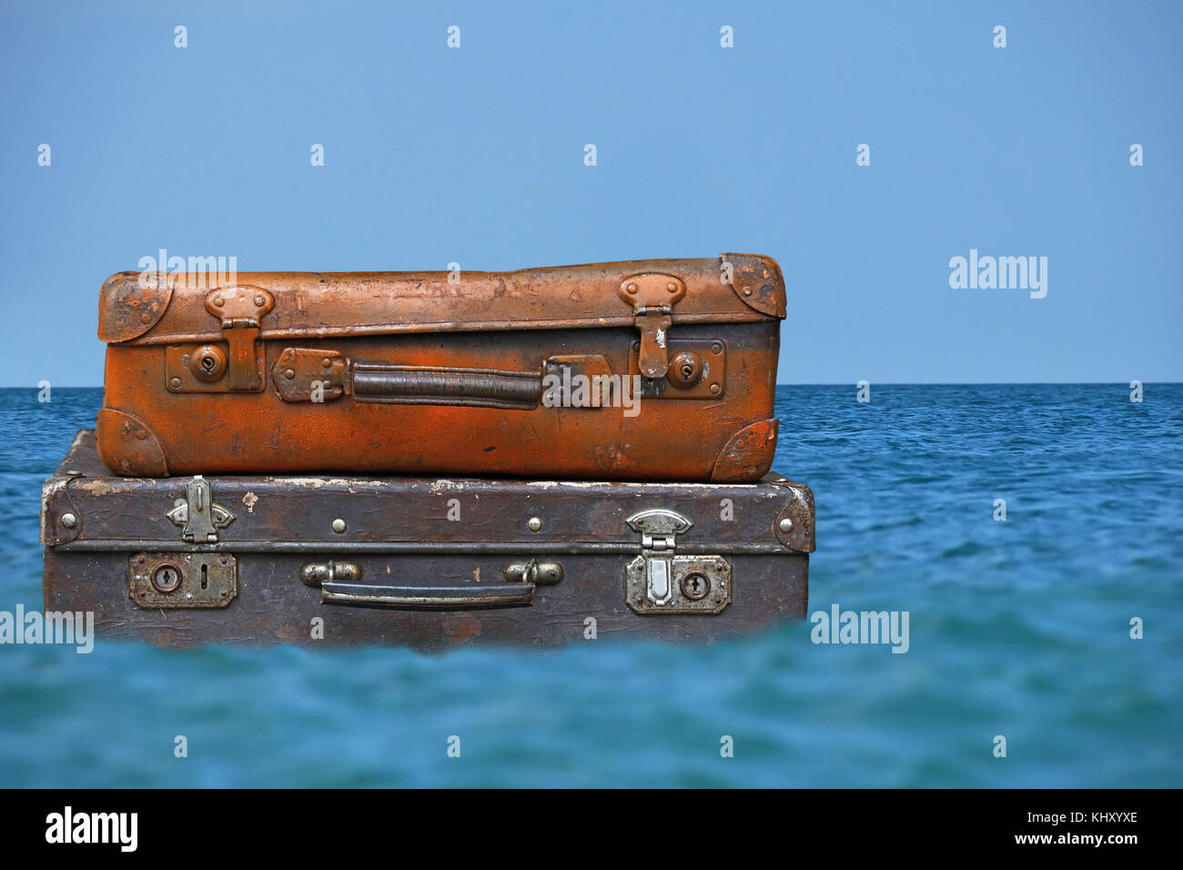 Stapel von zwei alten Vintage antik grunge Reisegepäck aus braunem Leder Koffer trunks Floating im blauen Meer Wasser unter klaren Himmel, Nahaufnahme, niedrigen Winkel s Stockfoto