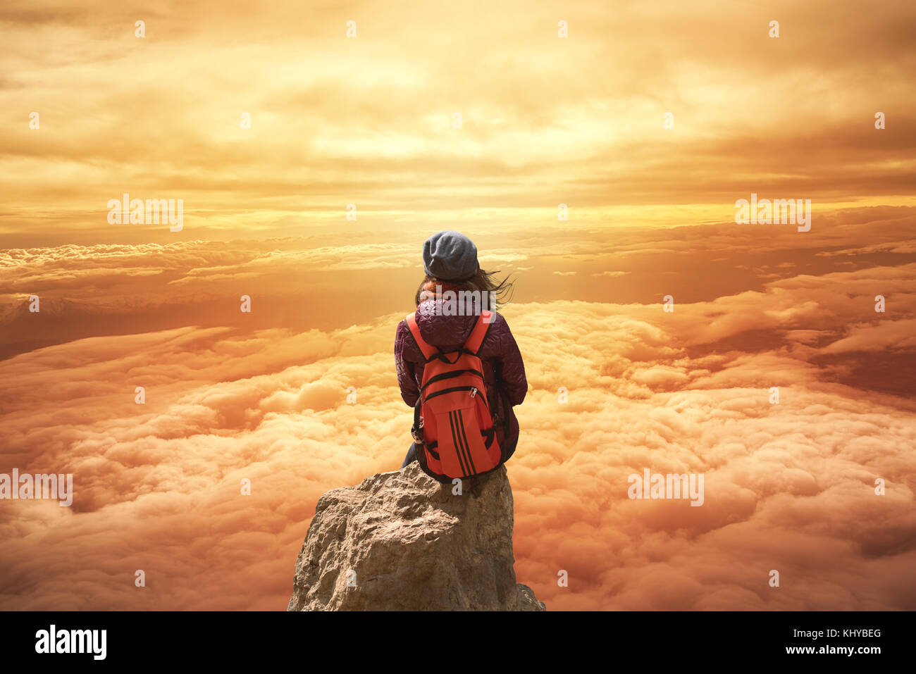 Junge Frau sitzt auf der Klippe und ein Himmel suchen Stockfoto