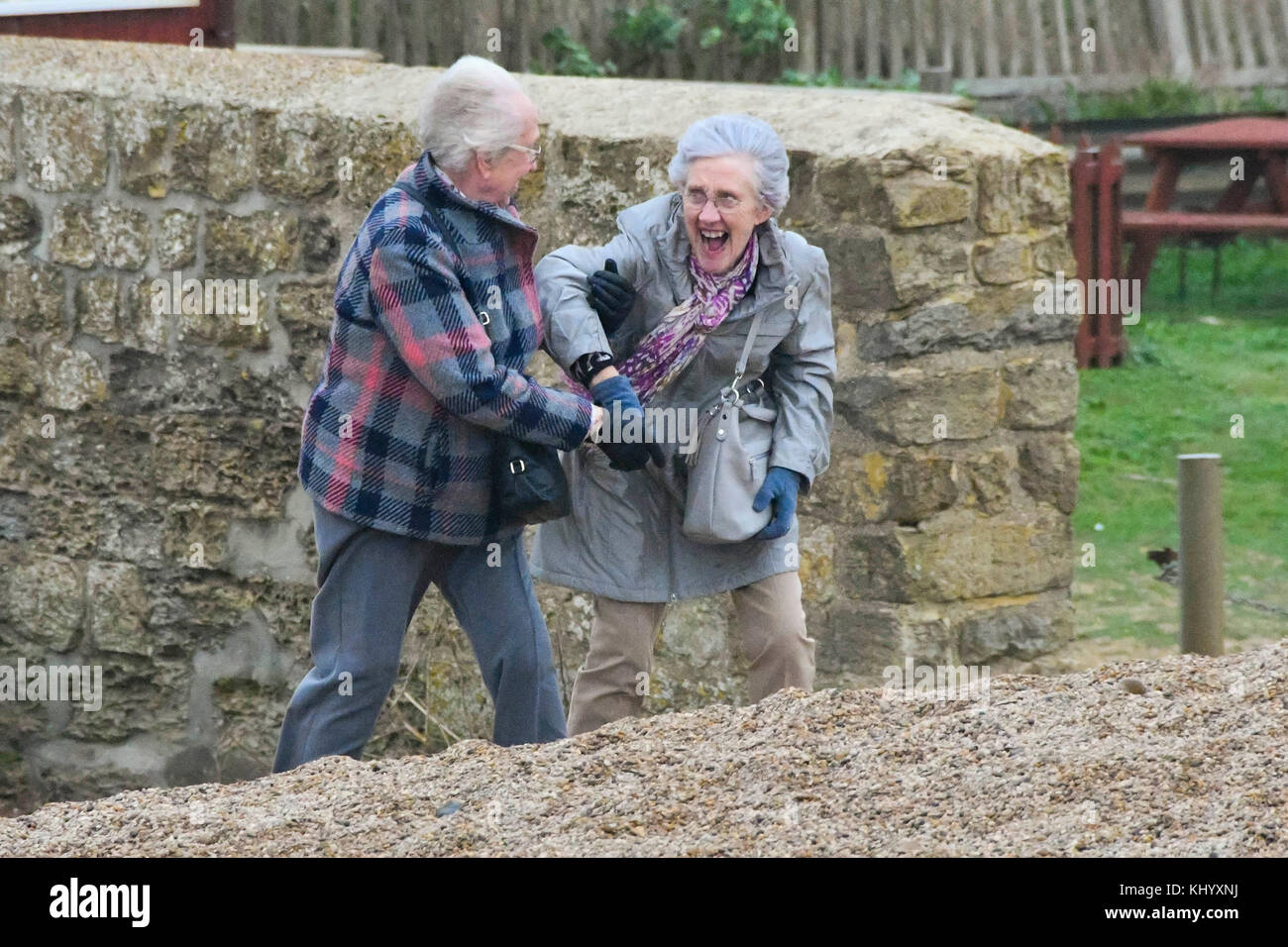 West Bay, Dorset, Großbritannien. 22. November 2017. UK Wetter. Zwei Frauen Kampf auf die East Strand von West Bay in Dorset zu Fuß, da Sie von stark böigem Wind an einem bewölkten Tag mit überdurchschnittlichen Temperaturen mitgenommen werden. Photo Credit: Graham Jagd-/Alamy leben Nachrichten Stockfoto