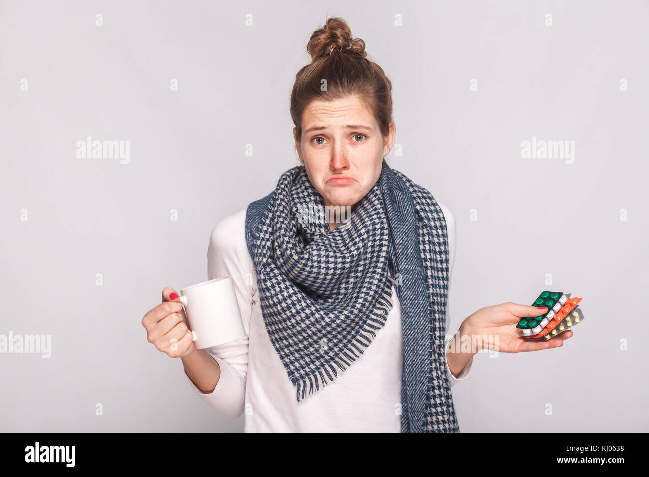 Sorge verwirrte Frau mit Tasse mit Tee, viele Pillen. studio Shot, auf grauem Hintergrund Stockfoto