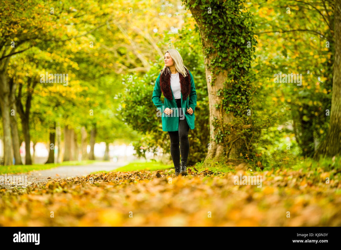 Jugendmädchen Modellierung in Großbritannien: Eine junge 16 jährige Pubertierende, trug einen Pelzbesatz grünen Mantel, Modellierung Walking im Freien an einem Herbsttag, Großbritannien Stockfoto