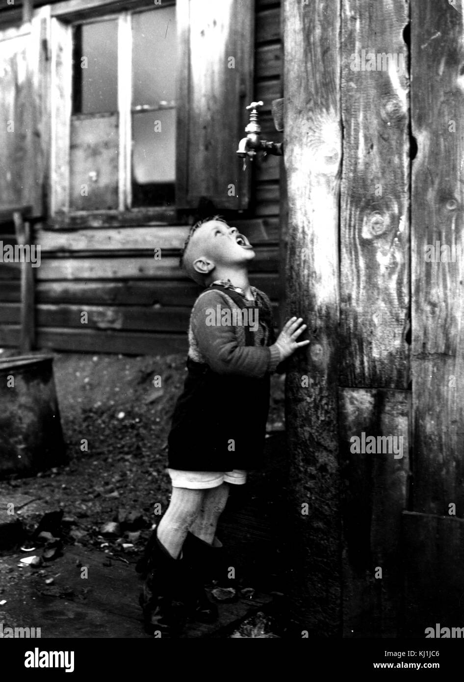 Foto von einem flüchtlingskind trinken aus einem Hahn, die alleinige Quelle von Wasser für die gesamte inoffizielle Flüchtlingslager als Bahnhofstrasse bekannt. Vom 20. Jahrhundert Stockfoto