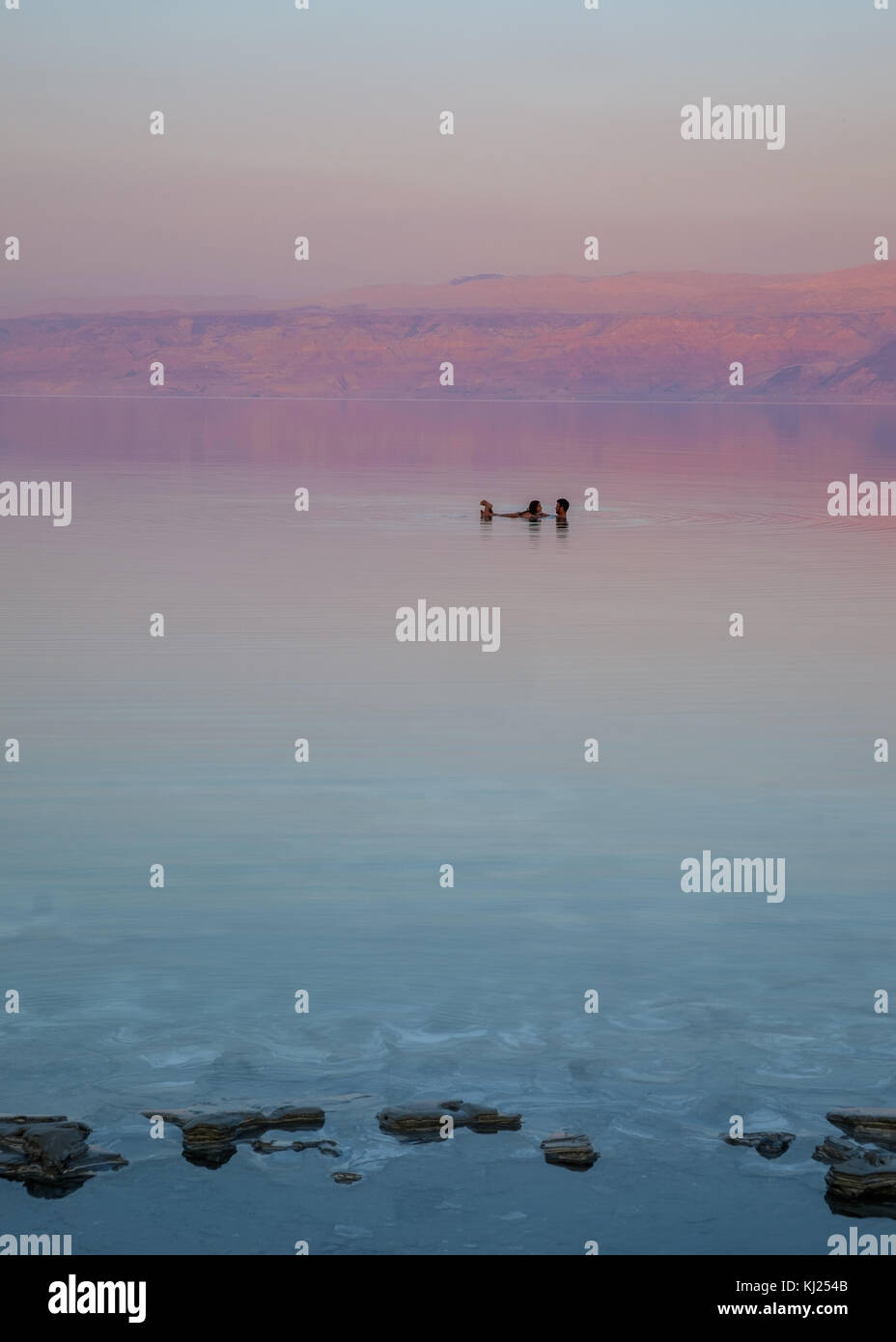 Liebhaber schwimmend auf dem Toten Meer bei Sonnenuntergang Zeit. Auf dem Hintergrund, den Jordan Berge verwandeln zu dieser Zeit des Tages rot. Stockfoto