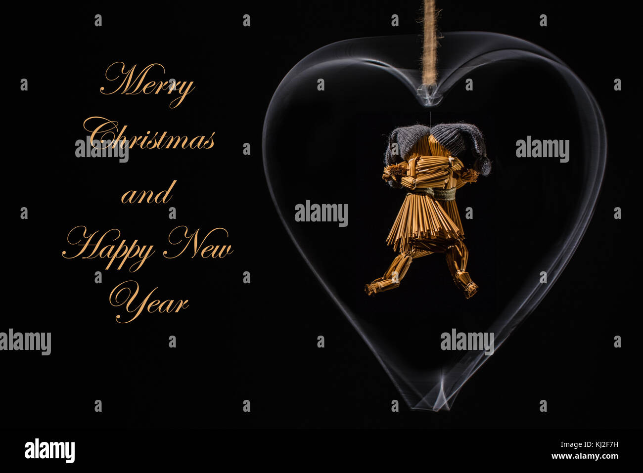 Weihnachtsgrüße mit Tanz Stroh Puppen in einem rotierenden Metal Heart und mit dem Text: Frohe Weihnachten und ein glückliches neues Jahr im Stroh/Gold Farbe Stockfoto