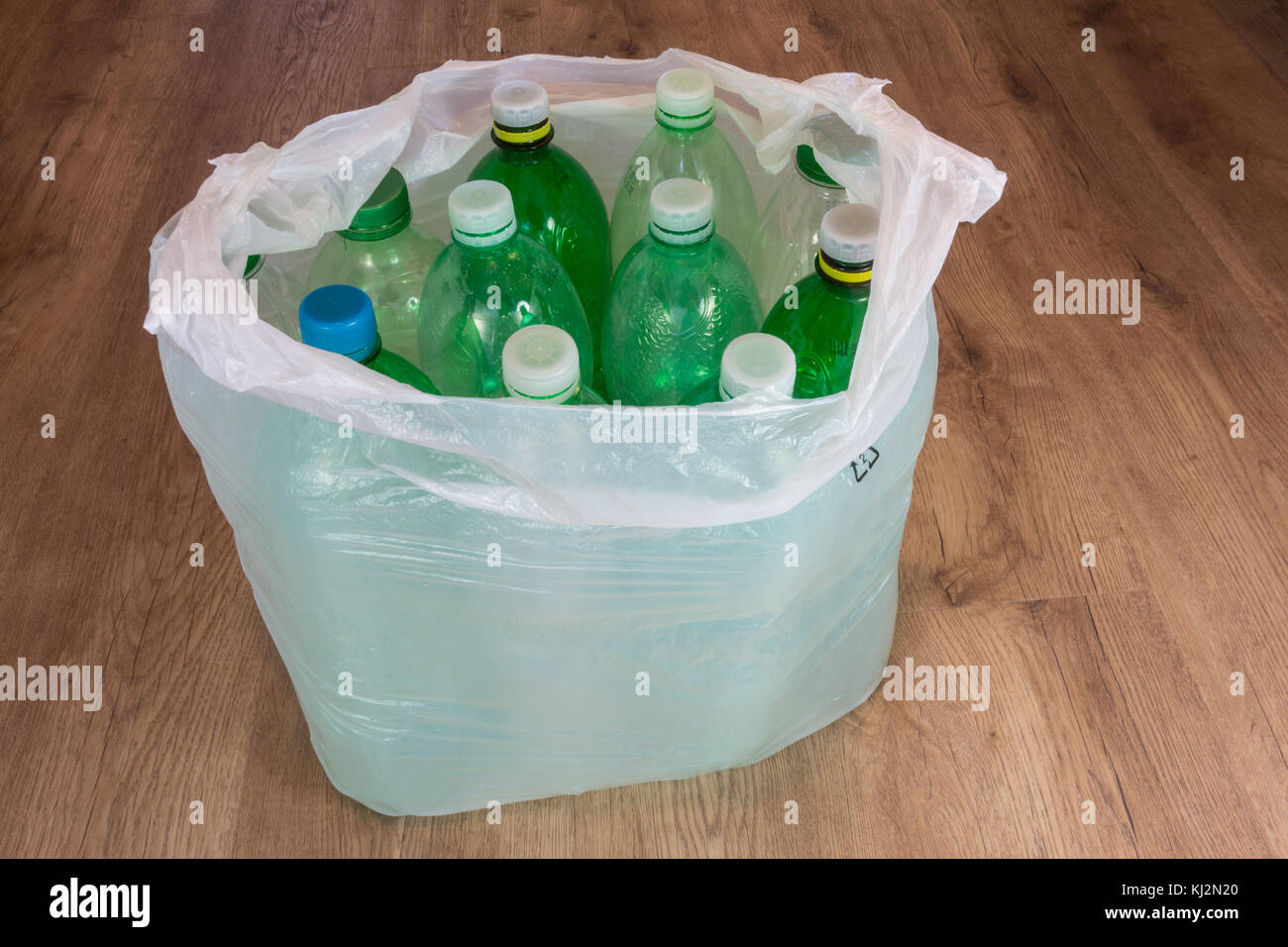 Grün Kunststoff Flaschen auf Holzboden. Ökologische Trennung von Hausmüll. leere PET-Flaschen in einen Plastikbeutel. Stockfoto