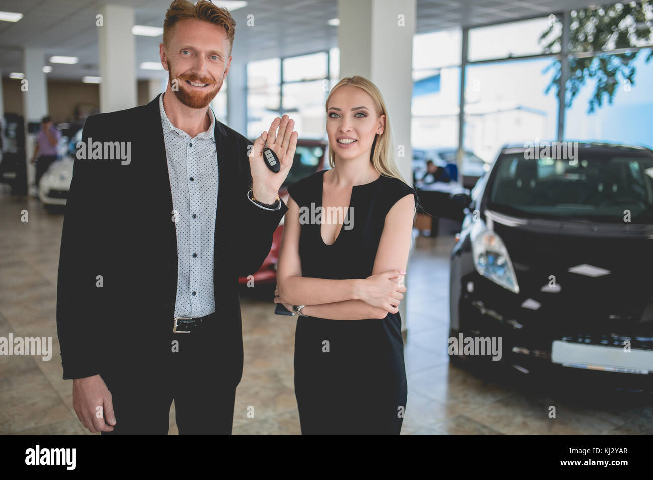 Junger Mann und Frau mit Schlüssel von neuen Elektro Auto. Stockfoto
