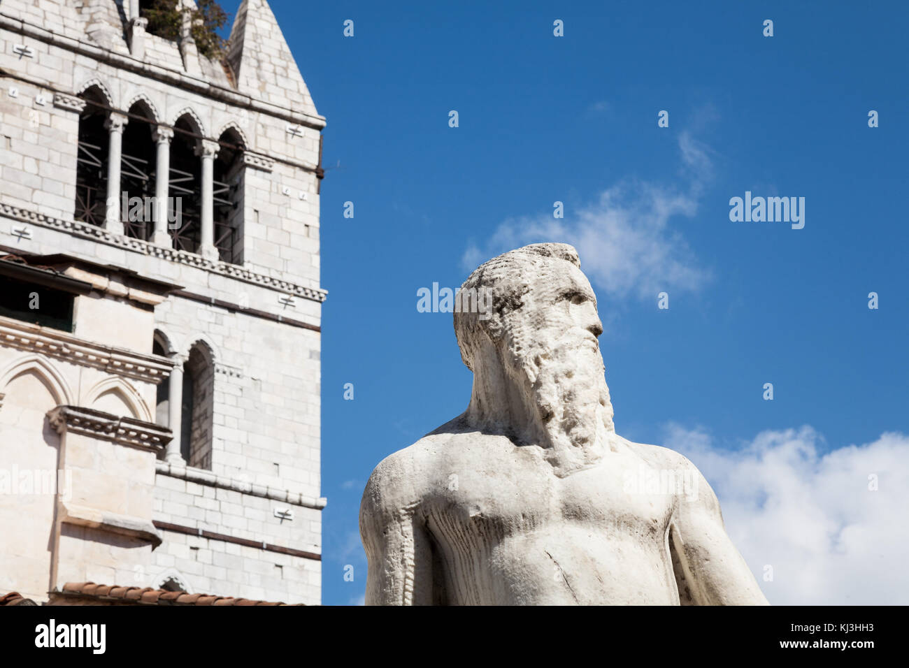 Die historische Marmorstatue des Riesen aus dem 16. Jahrhundert mit dem Domturm im Hintergrund in Carrara in der Toskana, Italien Stockfoto