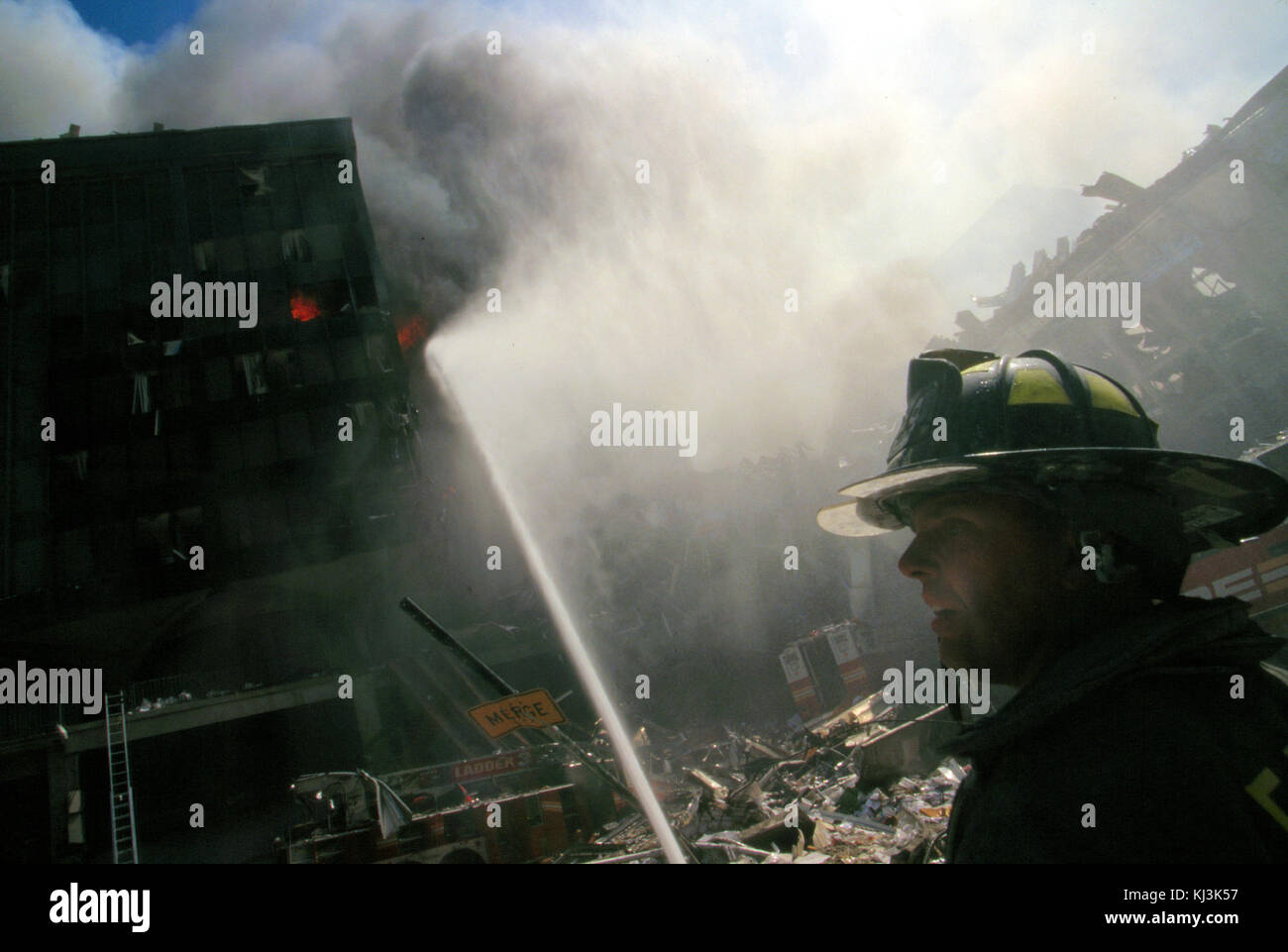 Feuerwehrmann sprüht Wasser auf brennendes Gebäude und Schutt nach dem Terroranschlag am 11. September auf Twin Towers, New York Stockfoto