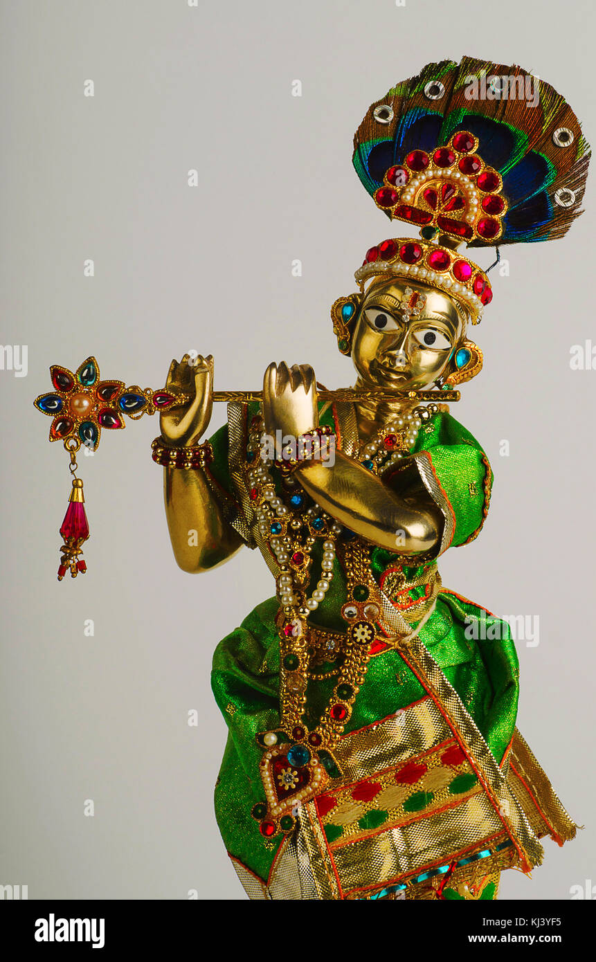 Messingstatue von Lord Krishna mit Flöte (Teilansicht) mit mukut oder Krone auf hellgrauem Hintergrund Stockfoto