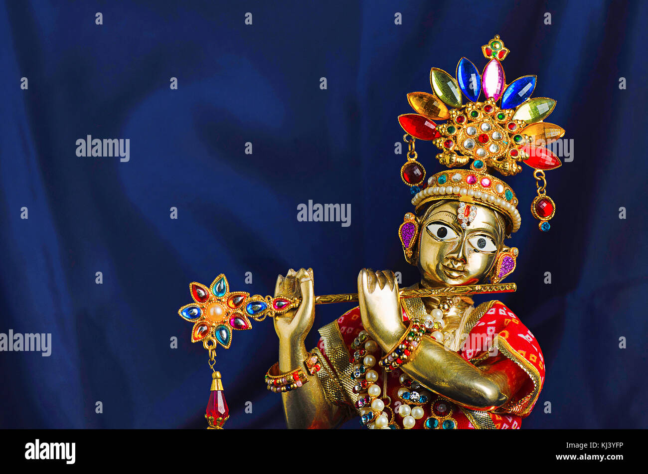 Messingstatue von Lord Krishna mit Flöte (Nahaufnahme) mit mukut oder Krone auf schwarzem Hintergrund Stockfoto