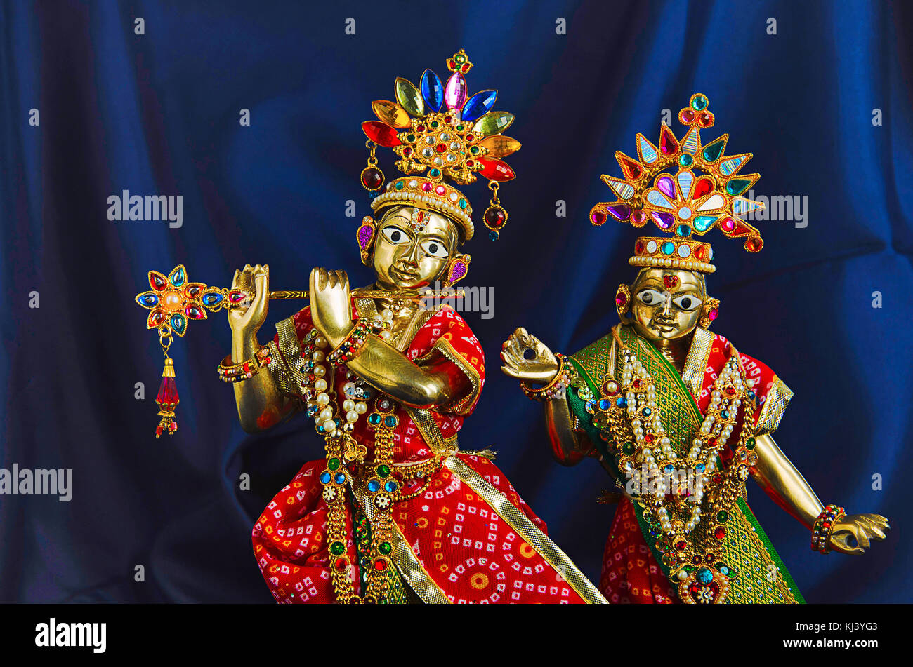 Messingstatue von Lord Krishna mit Flöte und Radha (Teilansicht) mit mukut oder Krone auf dunkelblauem Hintergrund Stockfoto