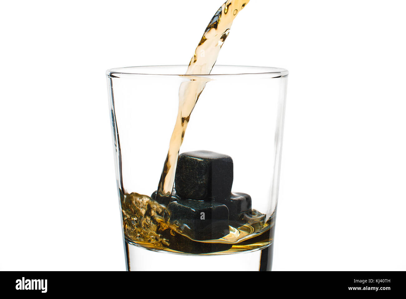 Whiskey gießt in ein Glas mit Steinen. Stockfoto