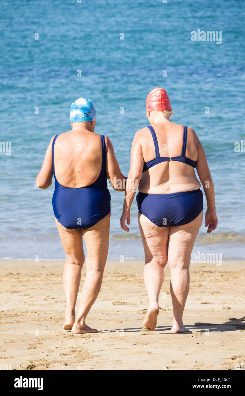 Rückansicht von älteren Frauen, die nach dem täglichen Keep-Fit-Kurs am Strand in Spanien schwimmen gehen Stockfoto
