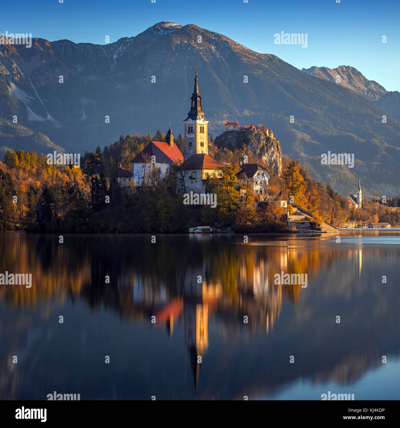 Bled, Slowenien - Schöner Herbstaufgang am Bleder See mit der berühmten Wallfahrtskirche Mariä Himmelfahrt und Schloss Bled und Julischen Alpen bei Stockfoto