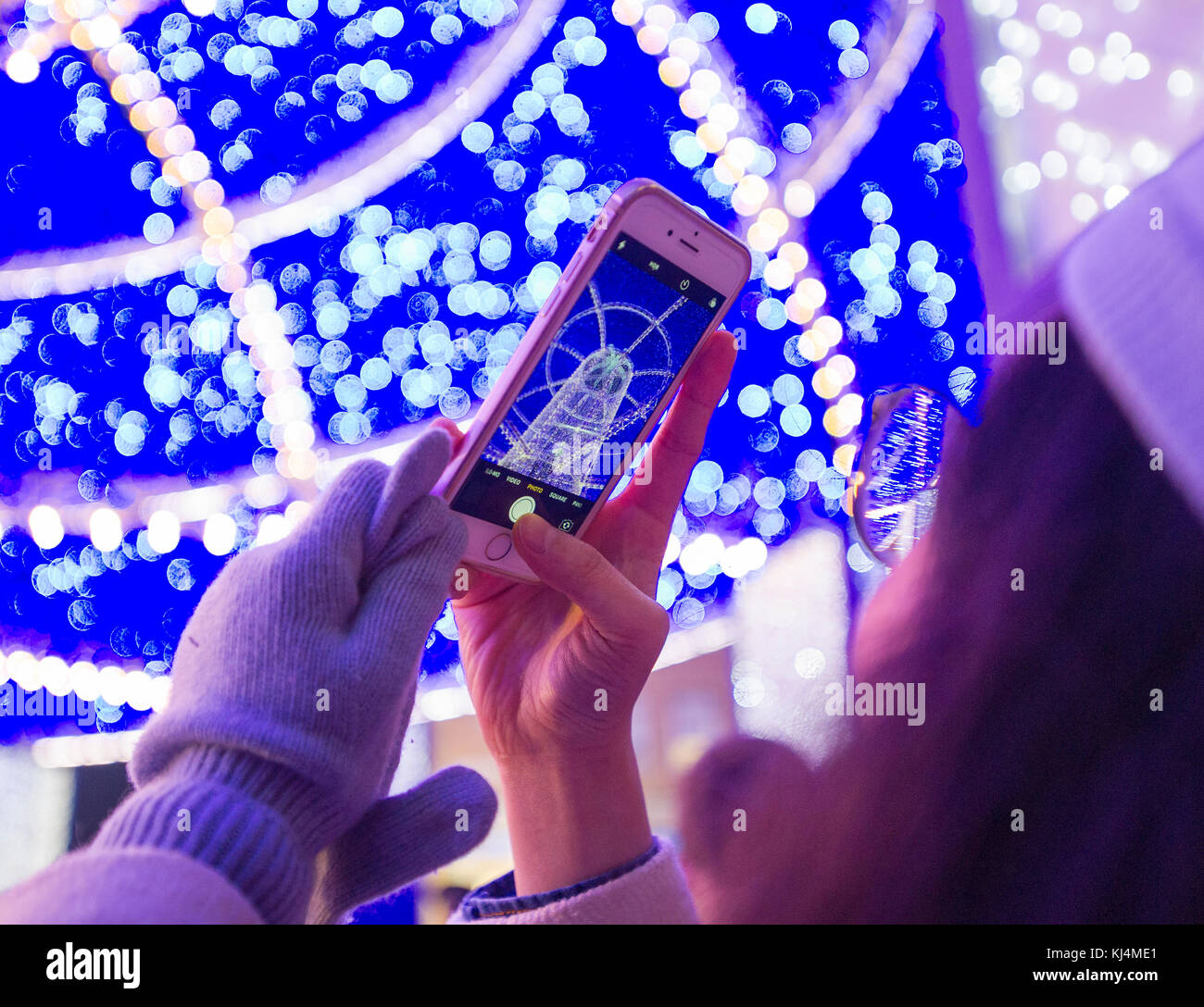 Ein Tourist nimmt ein Bild von der Weihnachtsbeleuchtung im Stadtzentrum von Edinburgh. Stockfoto