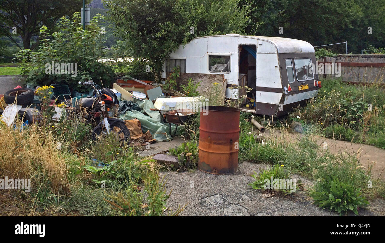 Eine alte verlassene verlassenen Wohnwagen und Motorrad plus andere Bits von Müll auf einem Stück überwucherte Land. Stockfoto