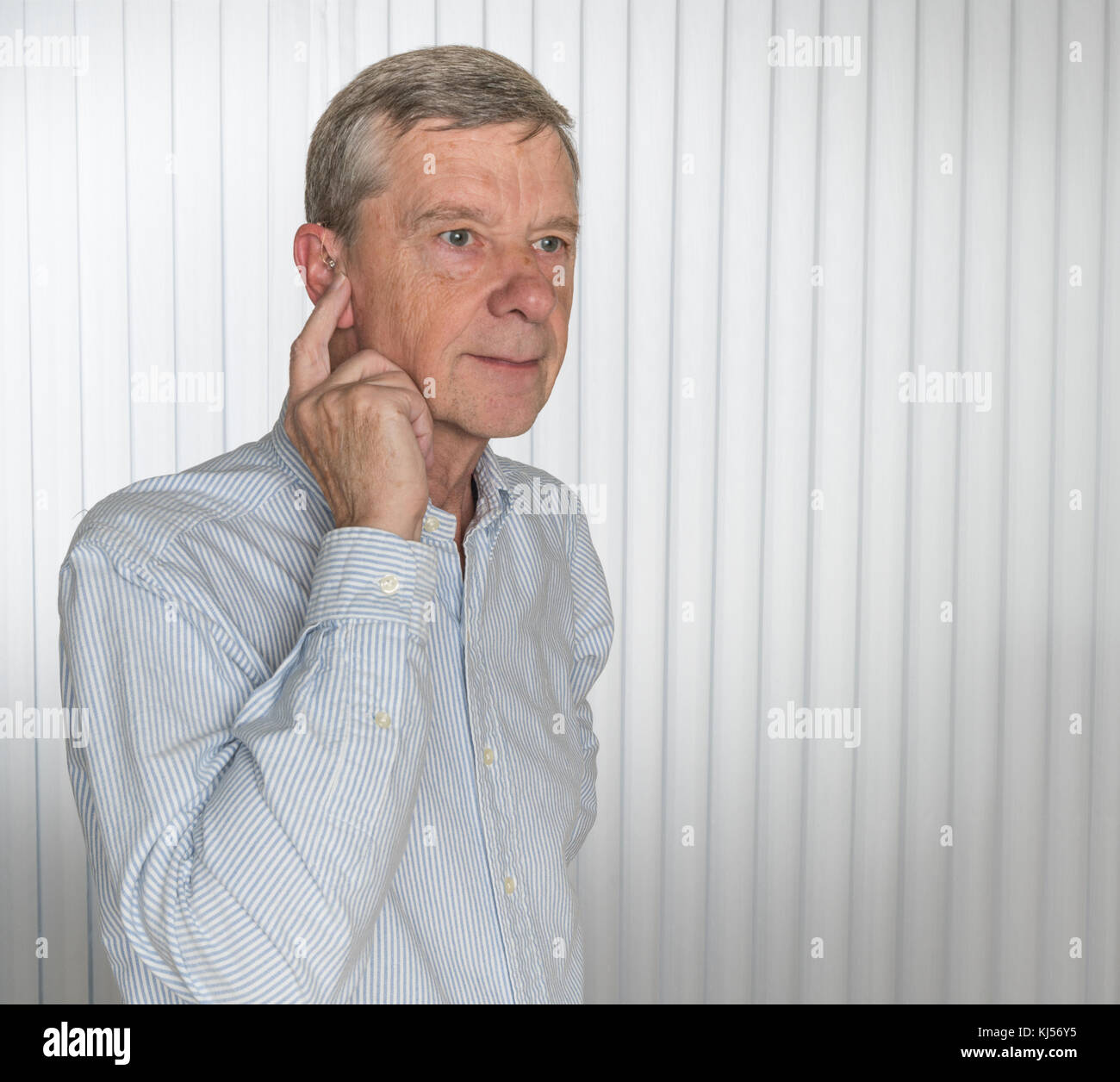 Nahaufnahme von einem winzigen modernen Hörgerät mit älterer Mann Stockfoto