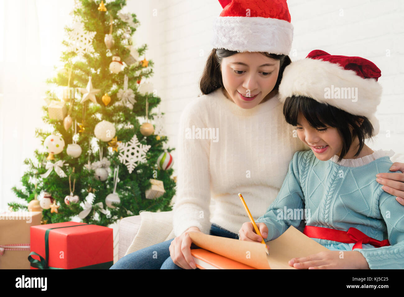 Frohe Weihnachten! Cute Asian Kind Mädchen und ihre Mutter schreiben Sie den Brief zusammen zu Santa Claus im Wohnzimmer zu Hause. Stockfoto