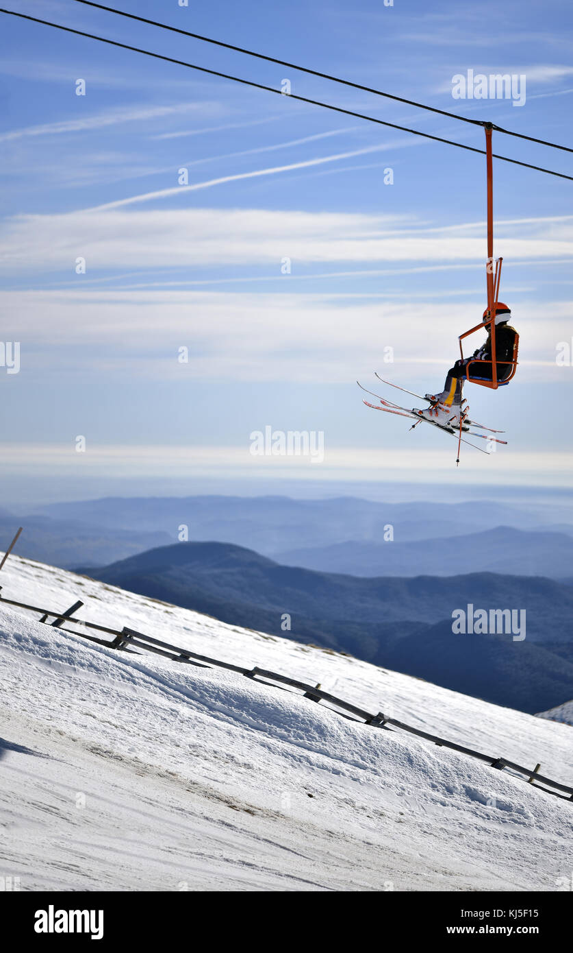 Skipiste mit klaren, blauen Himmel und Sesselbahn mit Skifahrer Stockfoto