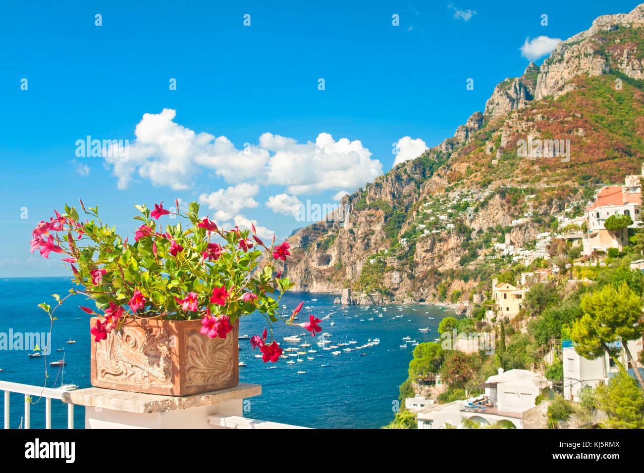 Blick auf Positano die Stadt, das Meer und die Berge vom Balkon mit Red Flower Pot im Vordergrund auf sonnigen Sommertag Stockfoto