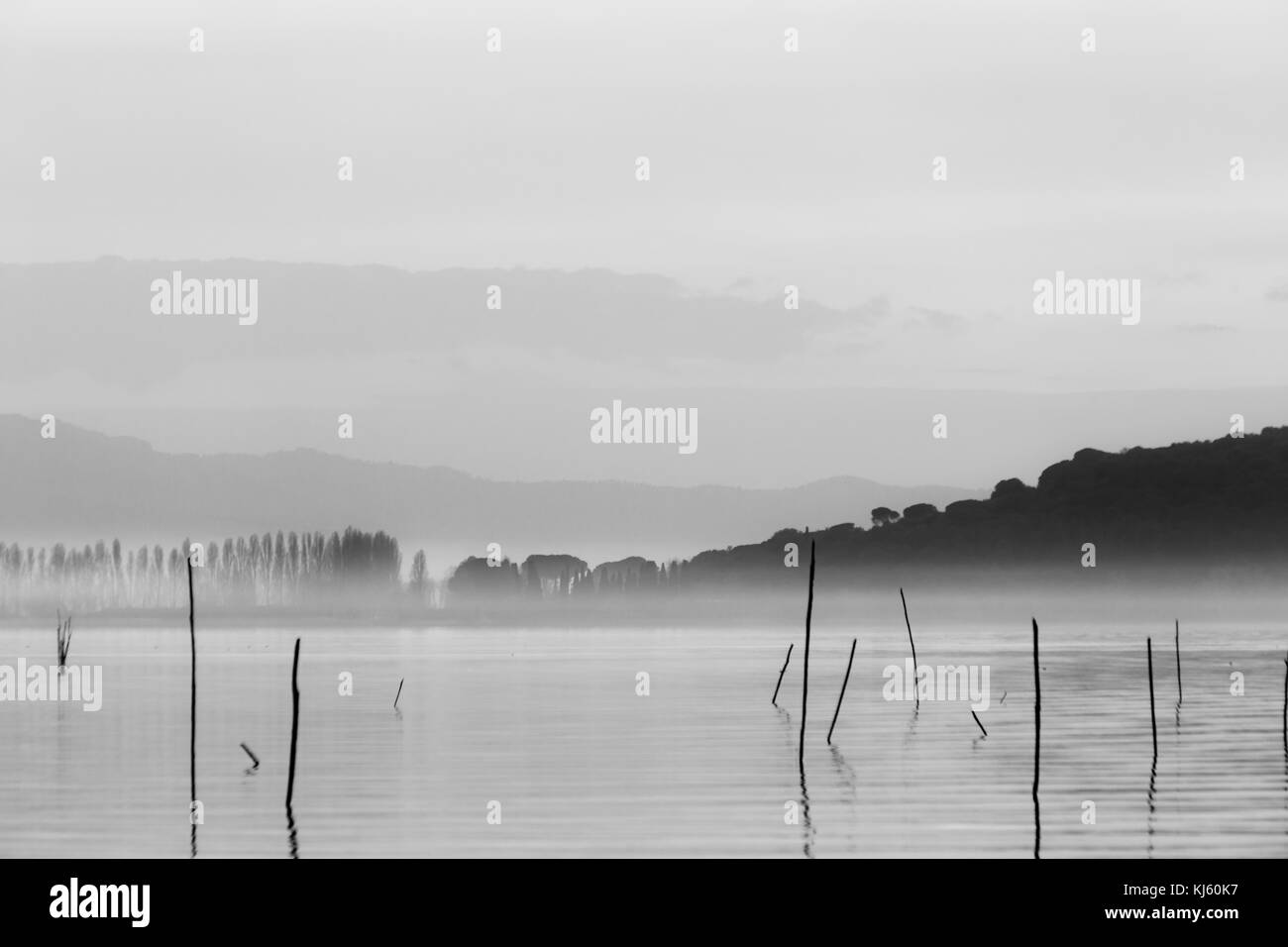 Ein See in der Abenddämmerung, mit sanften Farbtönen in den Himmel und Wasser und eine Insel in der Mitte des Nebels Stockfoto