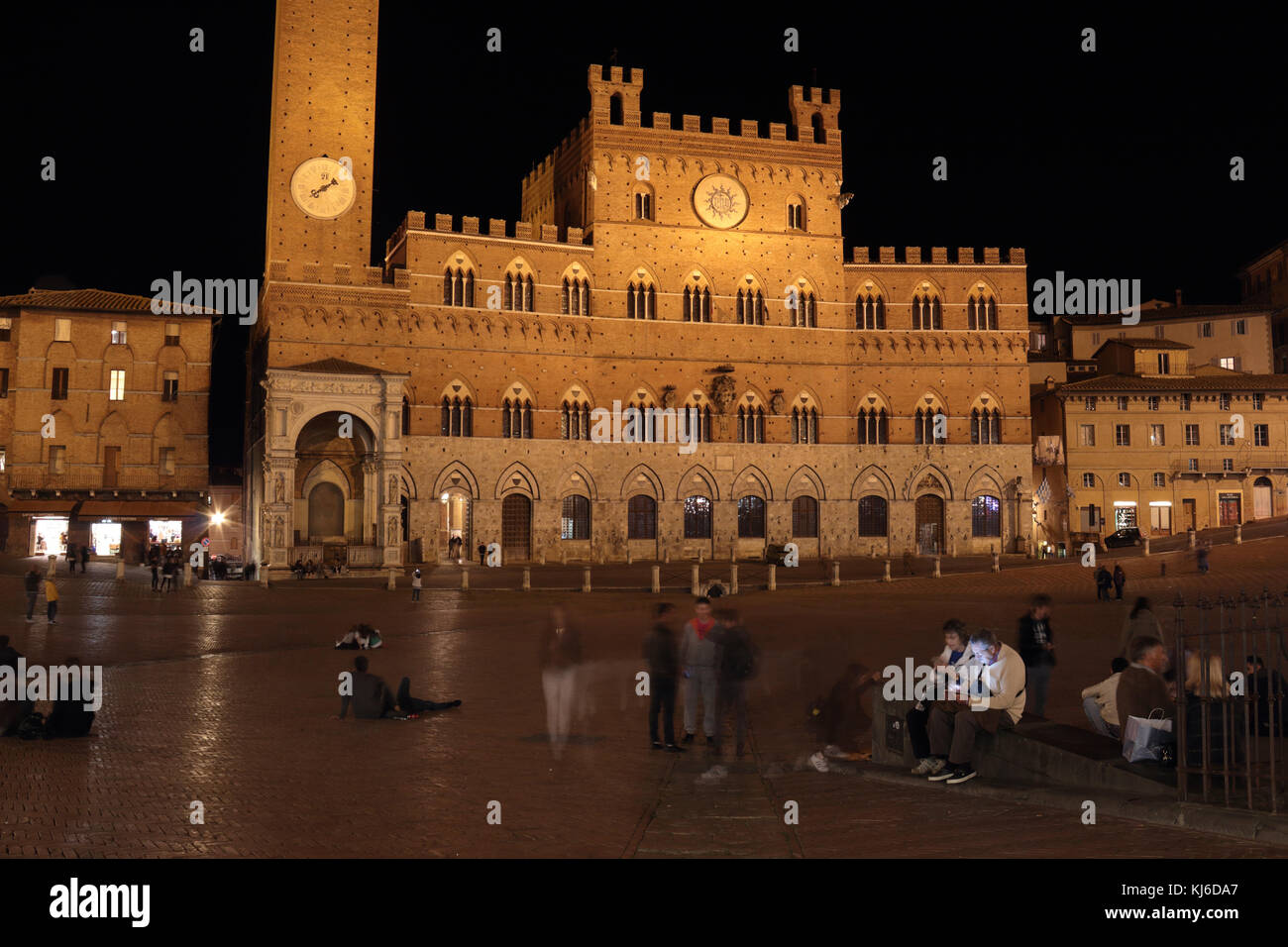 Menschen sitzen und gehen rund um die Piazza del Campo in Siena bei Nacht, Langzeitbelichtung. Stockfoto