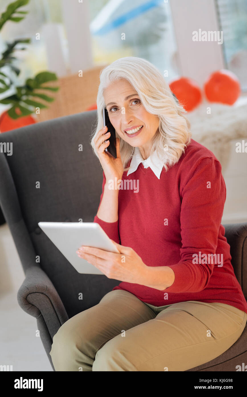 Schöne ältere Frau mit Touchpad beim Telefonieren Stockfoto
