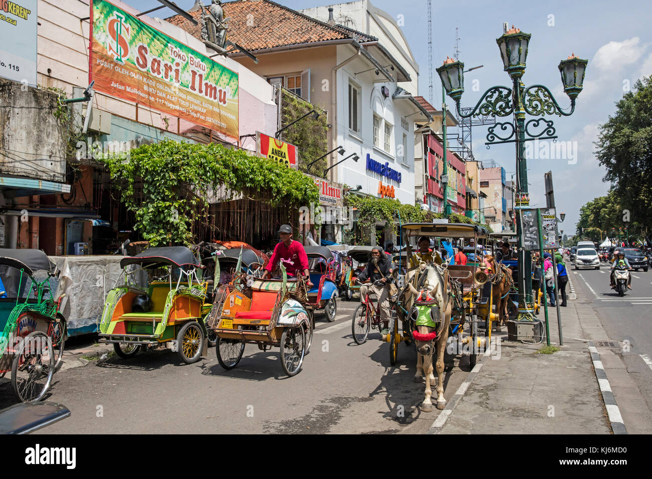 Zyklus Rikschas/becak und Pferdekutschen für den öffentlichen Verkehr in der Jalan Malioboro, wichtigsten Einkaufsstraße in Yogyakarta, Java, Indonesien Stockfoto
