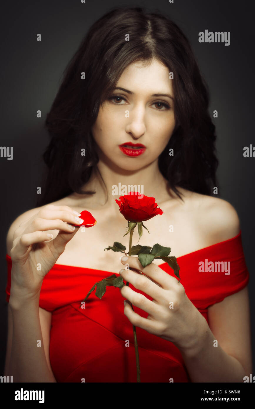 Frau die Blütenblätter ziehen weg eine rote Rose Stockfoto