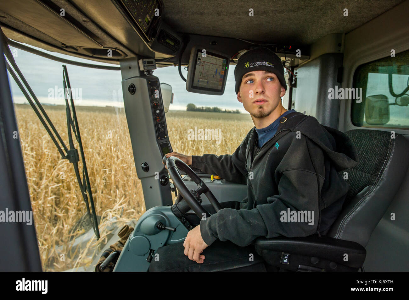 PORTRAIT VON JUNGEN Landwirt in der MÄHDRESCHERKABINE, BLOOMING Prairie, Minnesota. Stockfoto