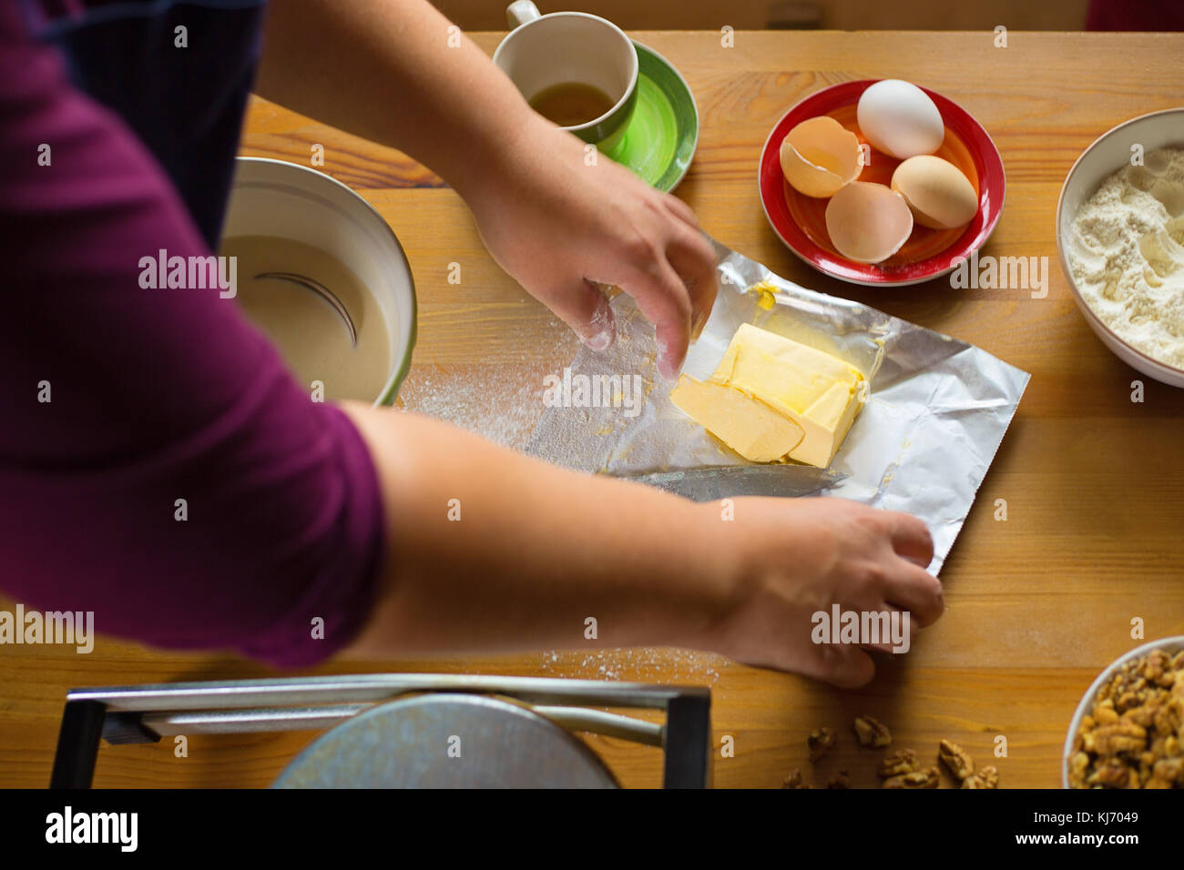 Weibliche Hände öffnen einer Butter Verpackung, Inhaltsstoffe auf dem Tisch Stockfoto