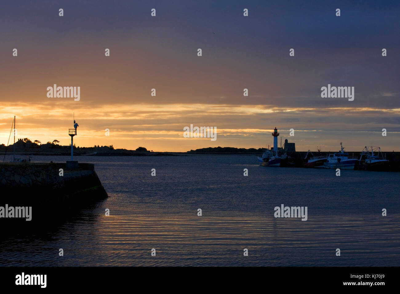 Hafen von St Vaast: Die Insel Tatihou und vertäute Fischerboote und Leuchtturm auf der Wellenbrecher in dramatischem sehr frühen Morgenlicht Stockfoto