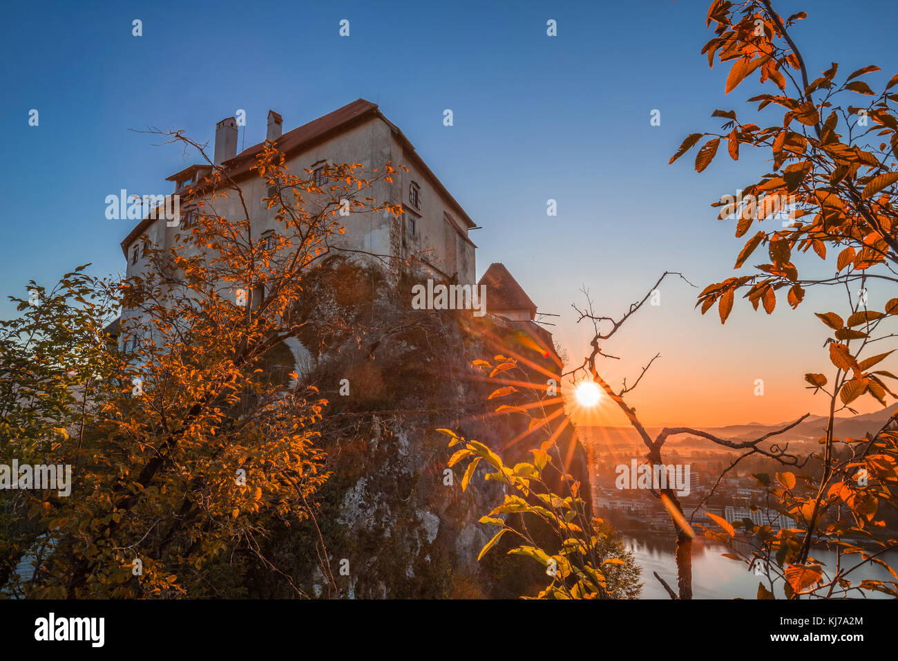 Bled, Slowenien - Schöner Sonnenaufgang auf Schloss Bled mit Blattwerk und Sonnenstrahlen Stockfoto